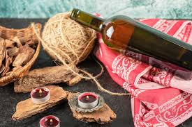 Rustic microsteading tools including candles, twine, and a bottle on a red cloth.